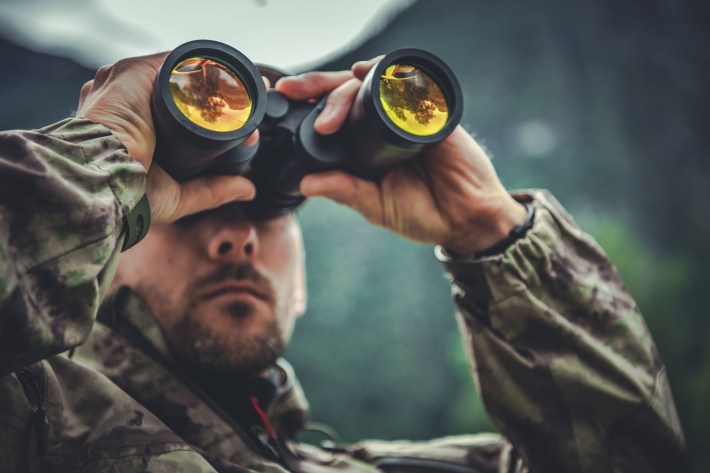 Caucasian Army Soldier in His 30s with Binoculars in Hands. Military Theme