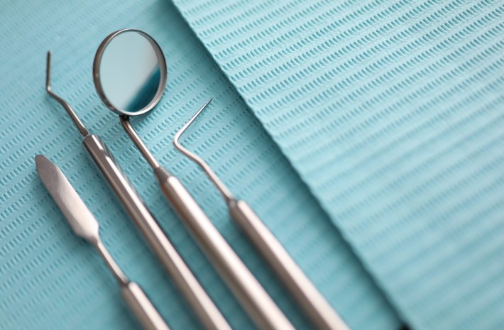 Pile of dentist tools lying at green tissue ready to be used close-up