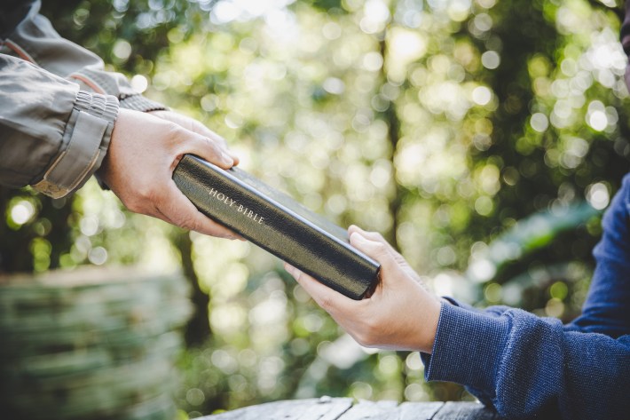 Handing a bible to a person who is interested in becoming a christian