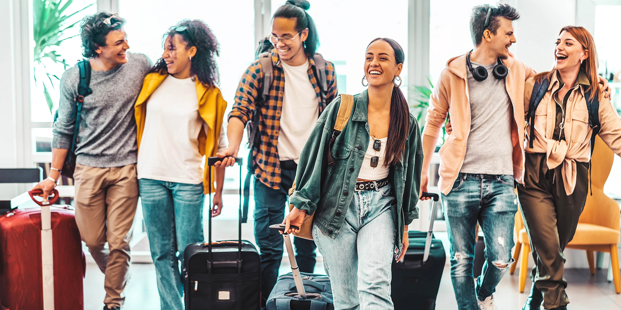 Young group of tourists with suitcases arriving at youth hostel guest house - Happy friends enjoying summer vacation together.