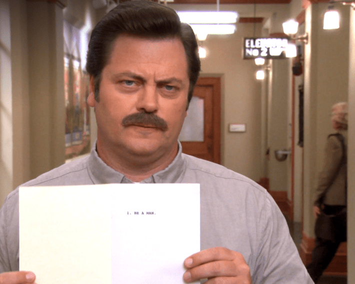 ron swanson holding a book open with a page that says "be a man"