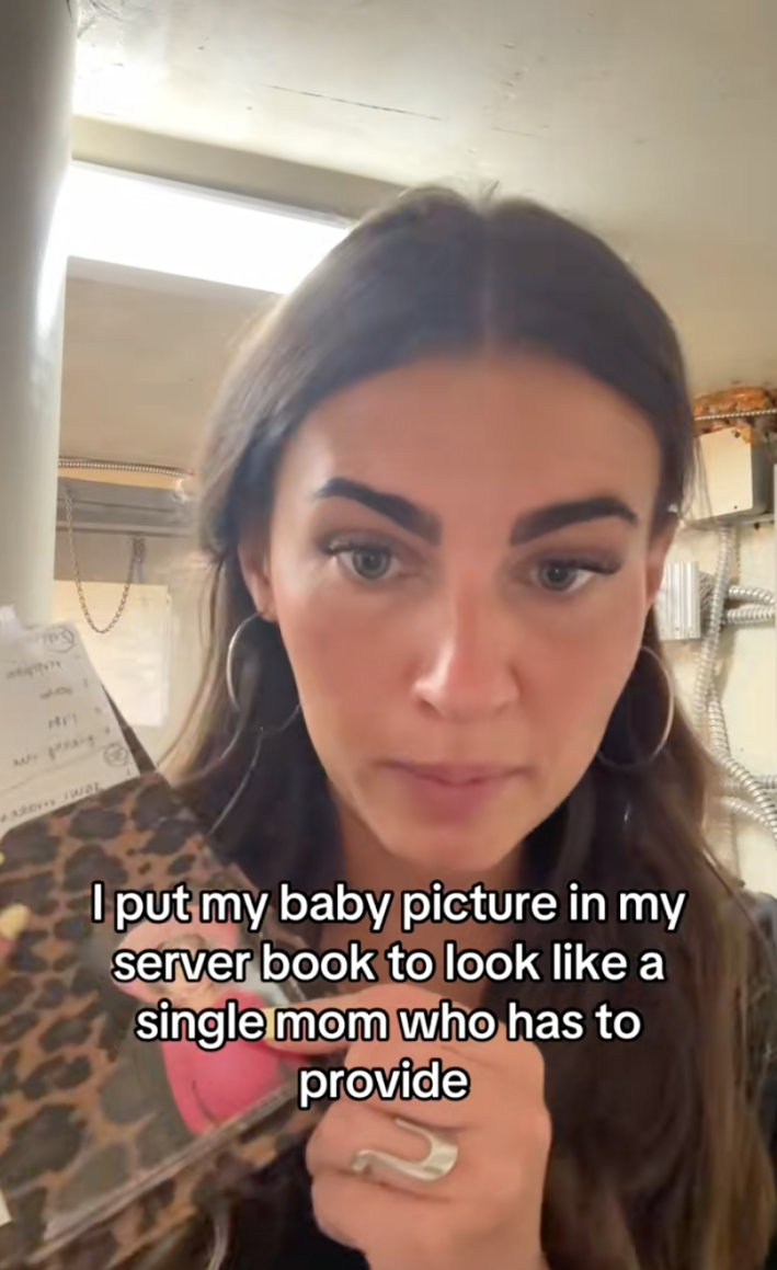 Woman pointing at her baby photo in her server book. Text overlay says, "I put my baby picture in my server book to look like a single mom who has to provide."