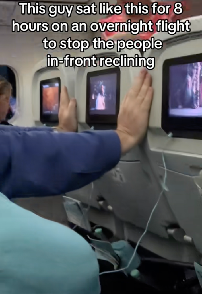 According to the video’s onscreen text, “This guy sat like this for 8 hours on an overnight flight to stop the people in-front from reclining.”