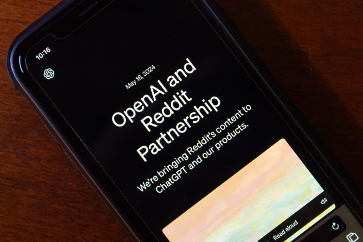 OpenAI and Reddit Partnership” from OpenAI website seen in an iPhone. OpenAI and Reddit partnered to enhance ChatGPT with Reddit content and improve Reddit using AI.