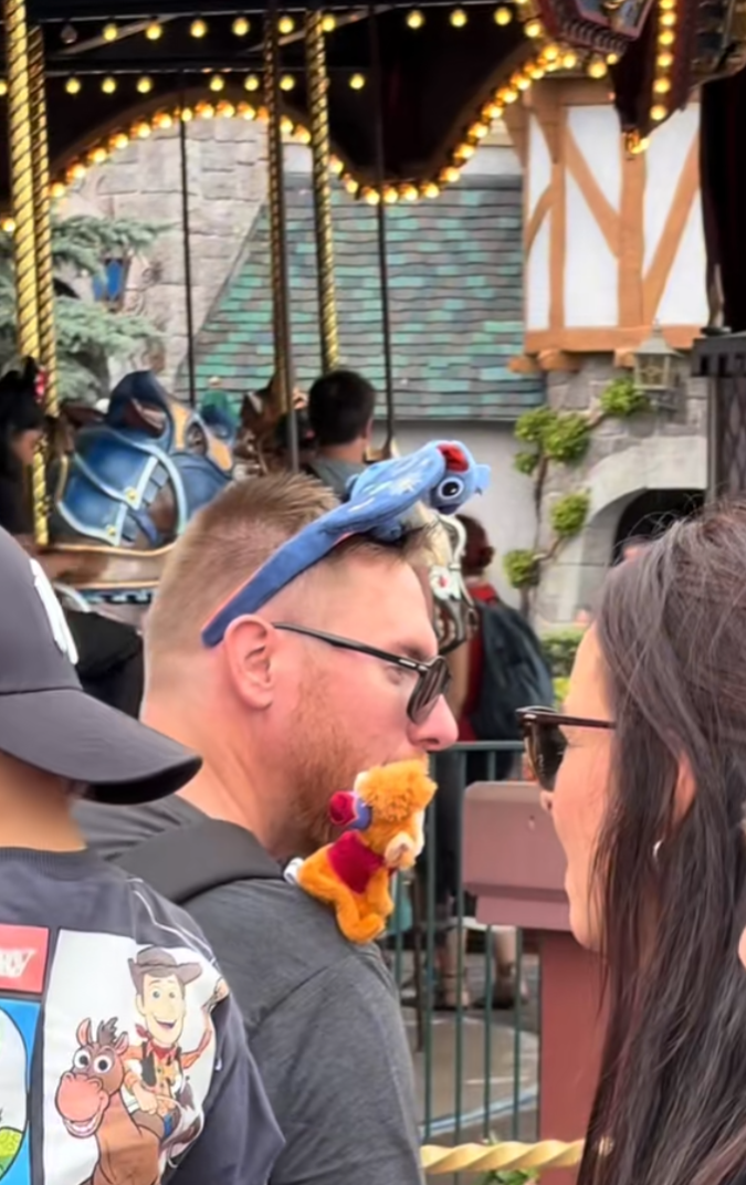 A man at a crowded Disney with Abu on his shoulder.