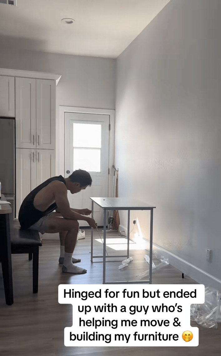 A man building a table in an empty apartment. Text overlay reads, "Hinged for fun but ended up with a guy who's helping me move & building my furniture."