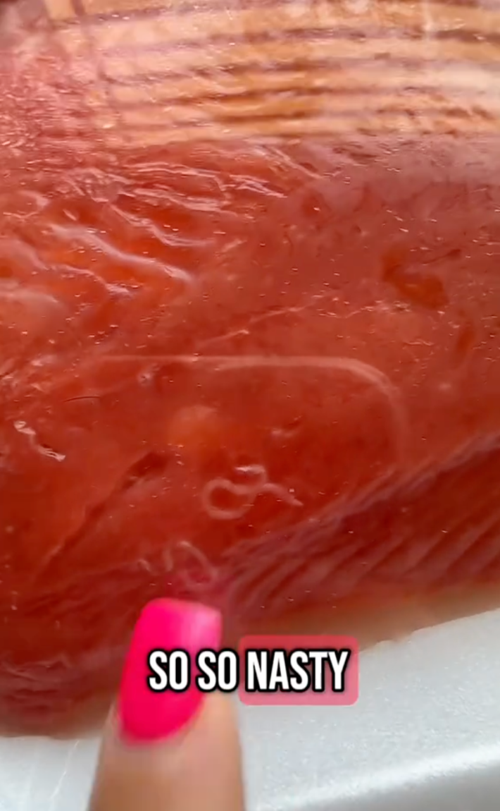 Screenshot of a salmon filet with parasites crawling around. Text overlay says, "So, so nasty."