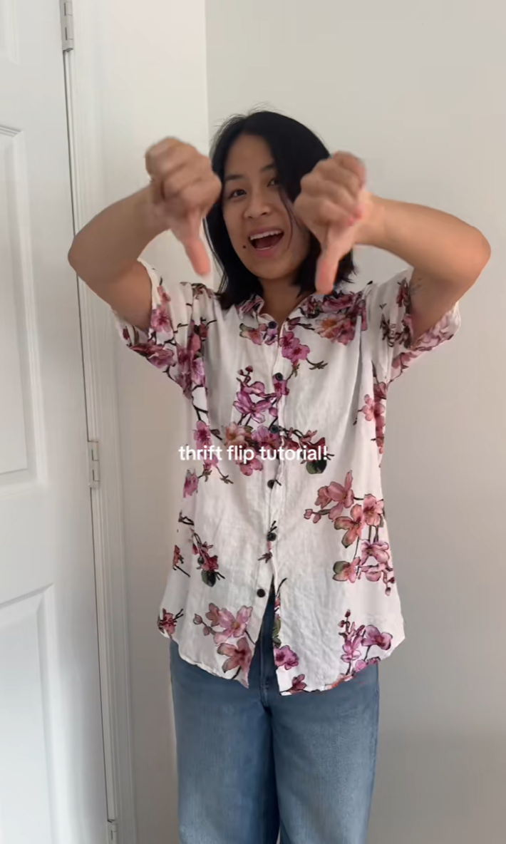 Smiley person wearing a floral top giving it a thumbs-down.