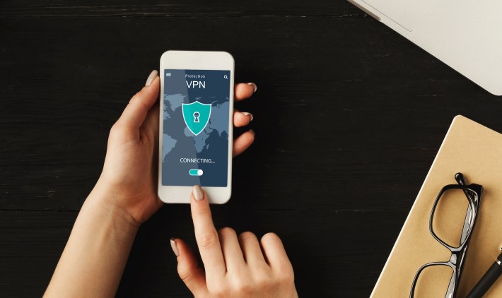 overhead view of woman holding and using smartphone with app vpn creation Internet protocols for protection, touching screen