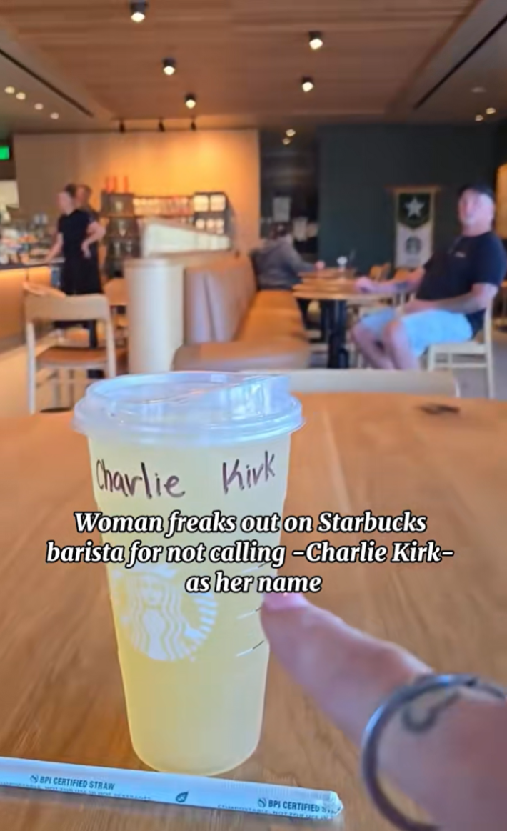 Woman pointing at her drink with "Charlie Kirk written on it.