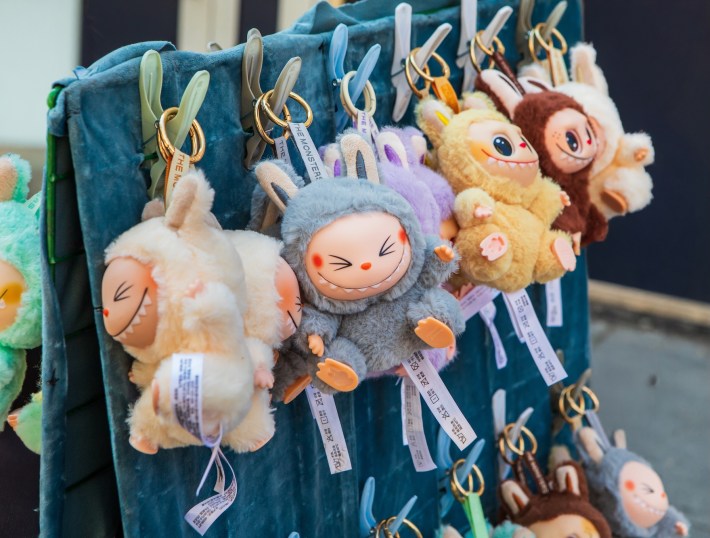 A collection of popular Labubu plush keychains, featuring various colors and expressions, hangs on display