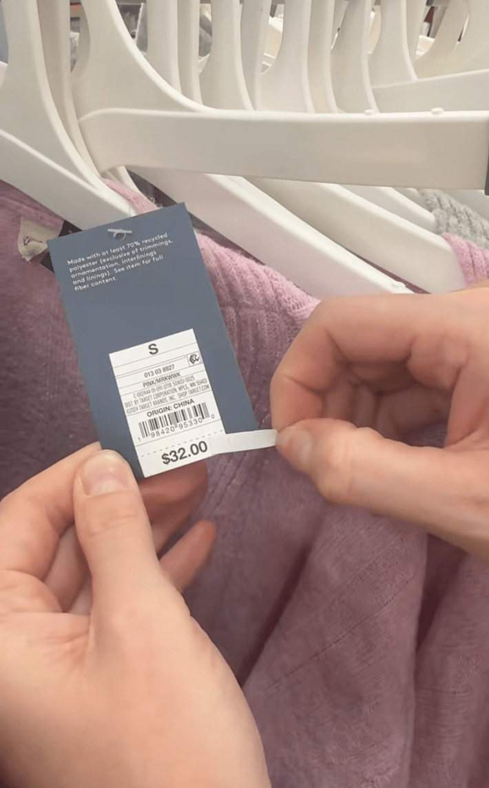 TikToker peeling the price sticker off a Target sweater to reveal a lower price.