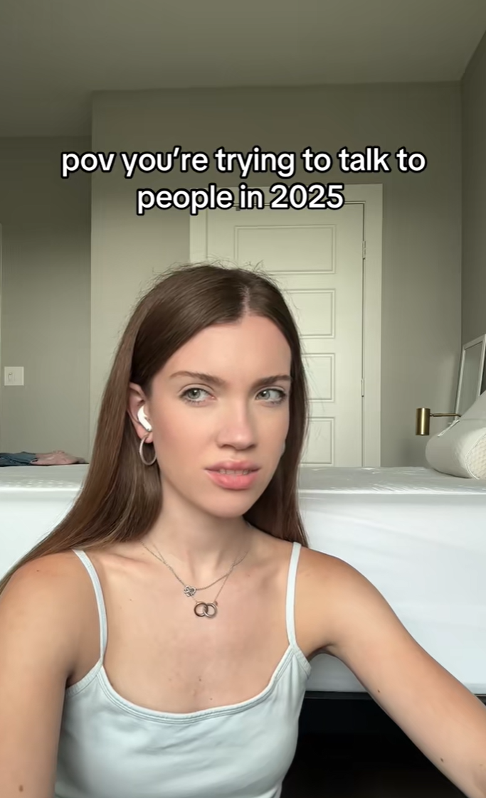 Young woman looking off to one side with a disgusted expression on her face. She is wearing headphones and sitting on her floor.