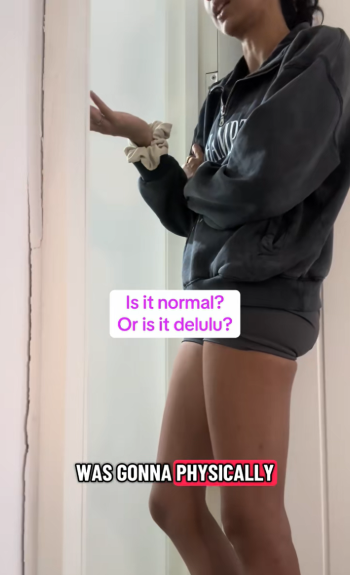 Woman leaning in her bedroom doorframe in a protective posture, gesturing with one hand as she talks to her family in the other room.