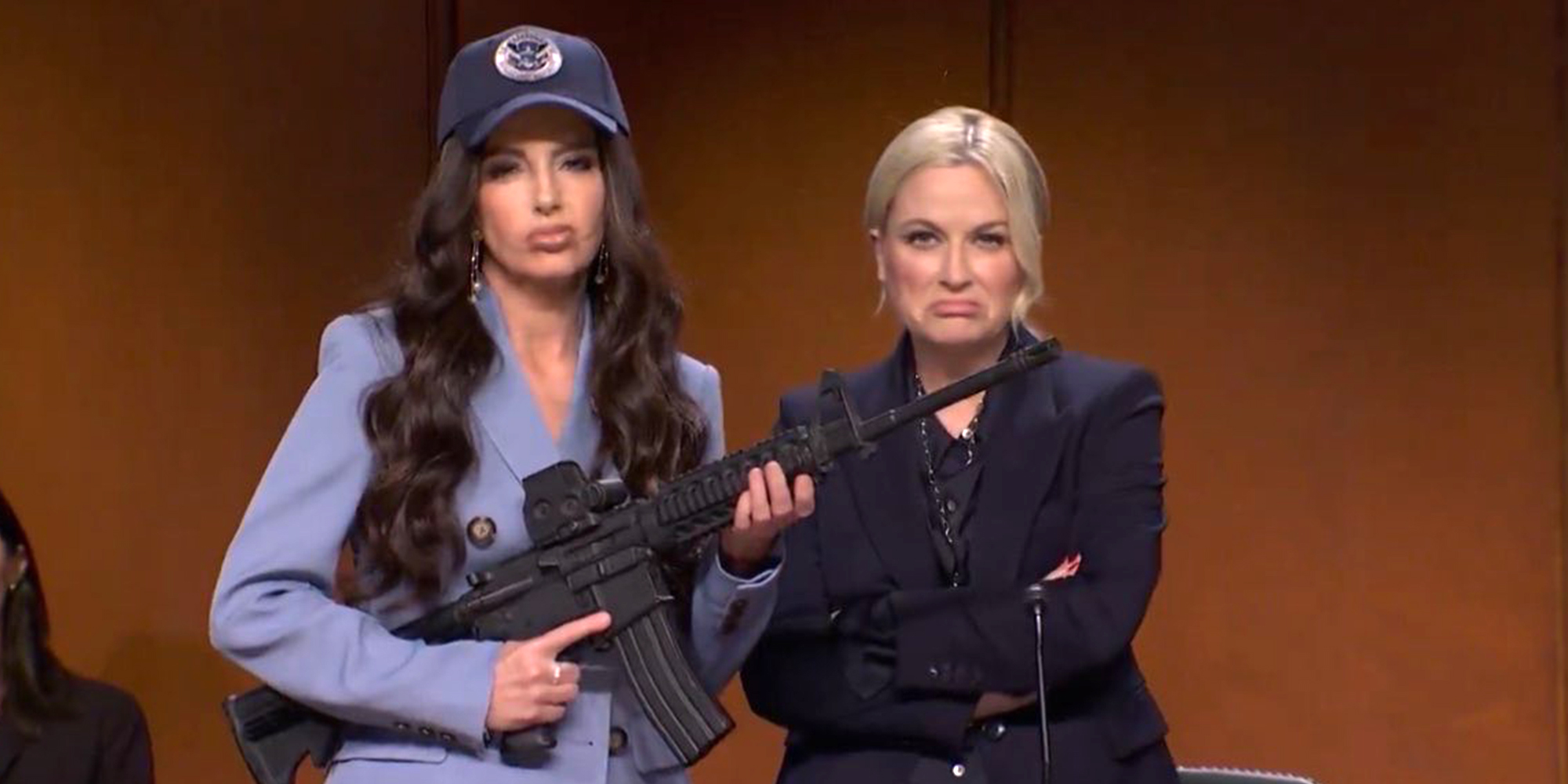Tina Fey and Amy Poehler on October 11, 2025 episode of "Saturday Night Live." Fey is holding an automatic weapon, parodying Kristi Noem, and Amy Poehler is parodying Attorney General Pam Bondi.