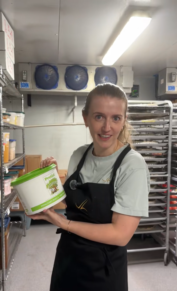 The bakery owner showing off the 100% pistachio filling container.