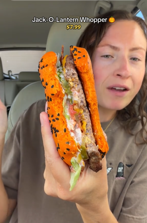 TikTok video of a woman in her car holding up a partially eaten Jack-O-Lantern Whopper.