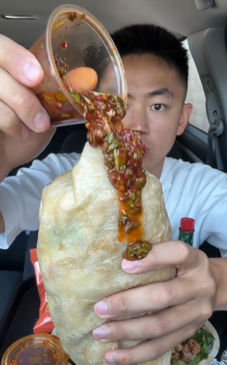 TikTok video of a man pouring Chipotle's Red Chimichurri sauce on a burrito.