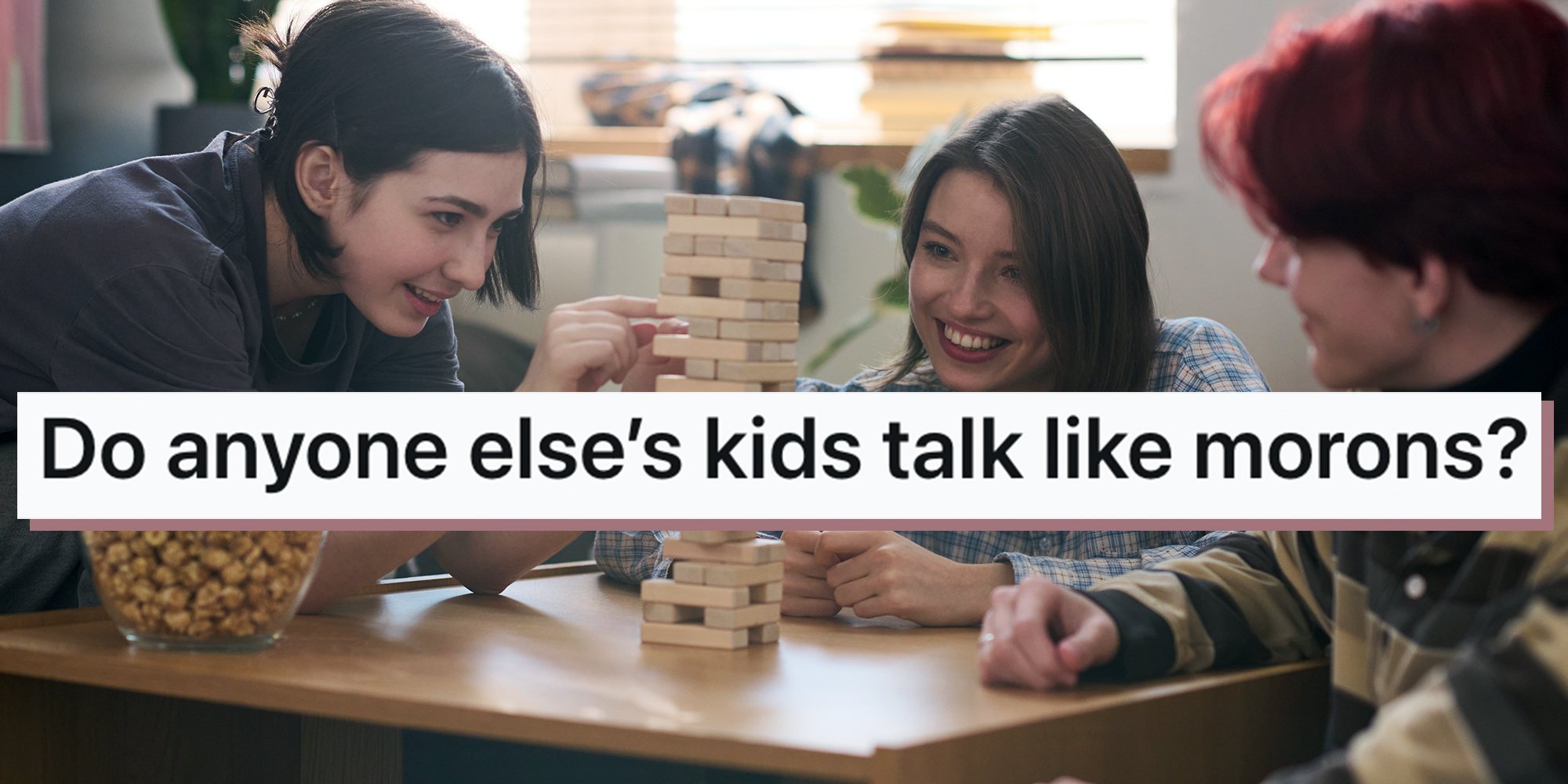 Smiling teenage girl playing board game with two friends at home or in school dorm and removing wooden block from tower. Text overlay from Reddit reads, "Do anyone else’s kids talk like morons?"