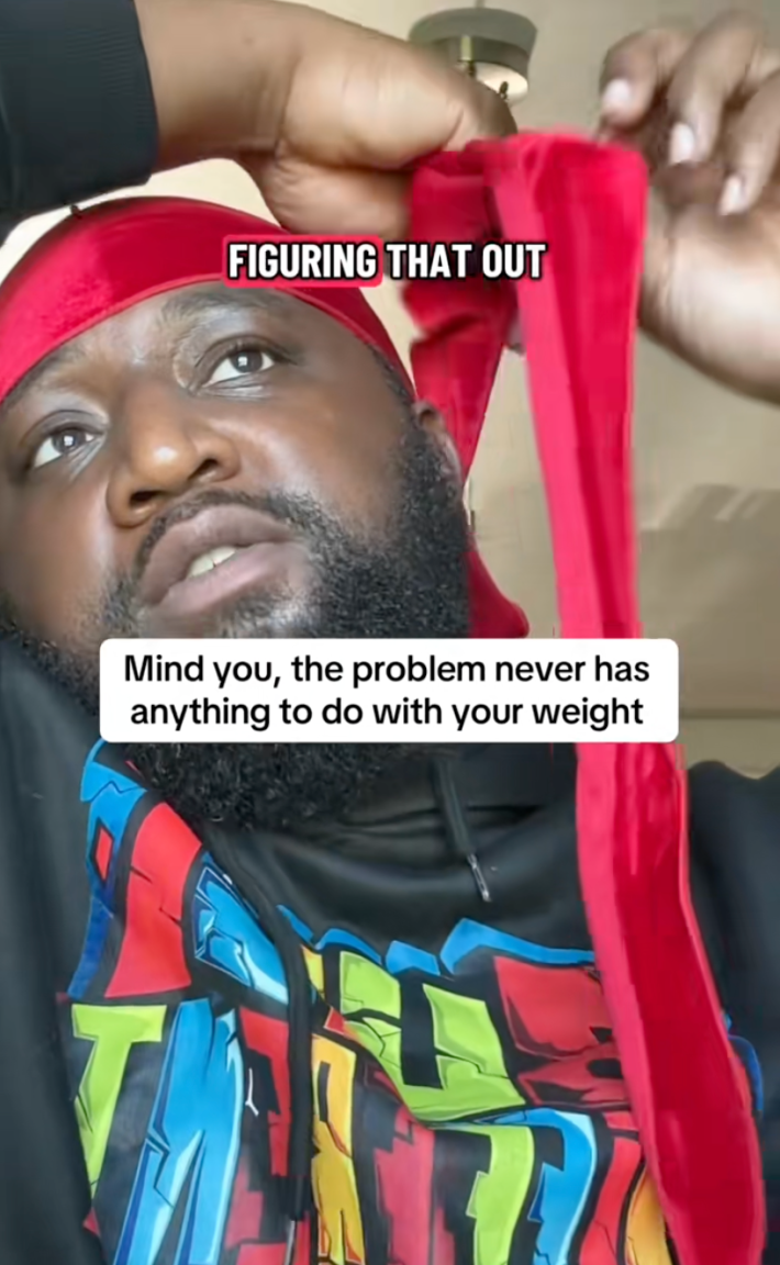 A Black man wrapping his durag while he talks to the camera about women's health. Text overlay reads, "Mind you, the problem never has anything to do with your weight"
