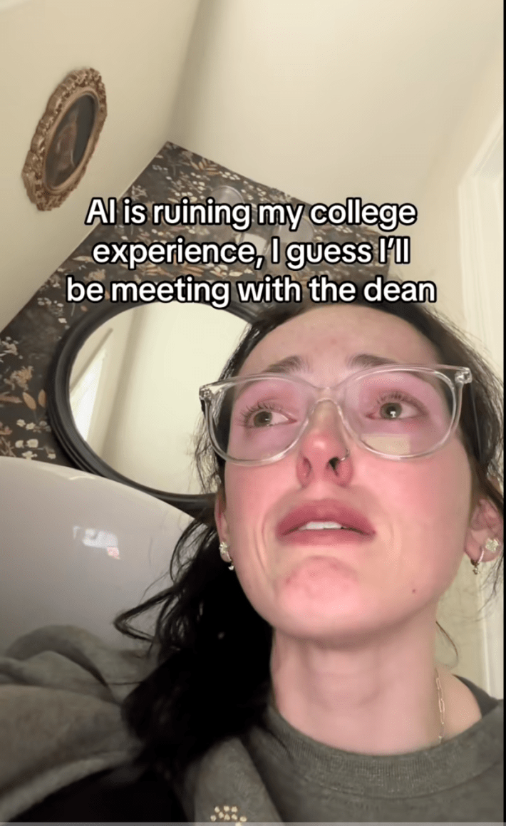 Upset college student in big glasses crying and looking off screen.