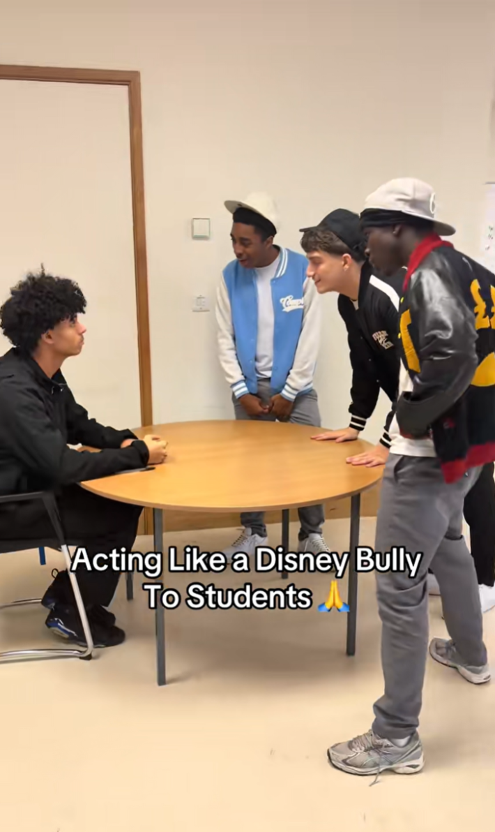 Group of "bullies" making fun of another person sitting at a round table at a school.