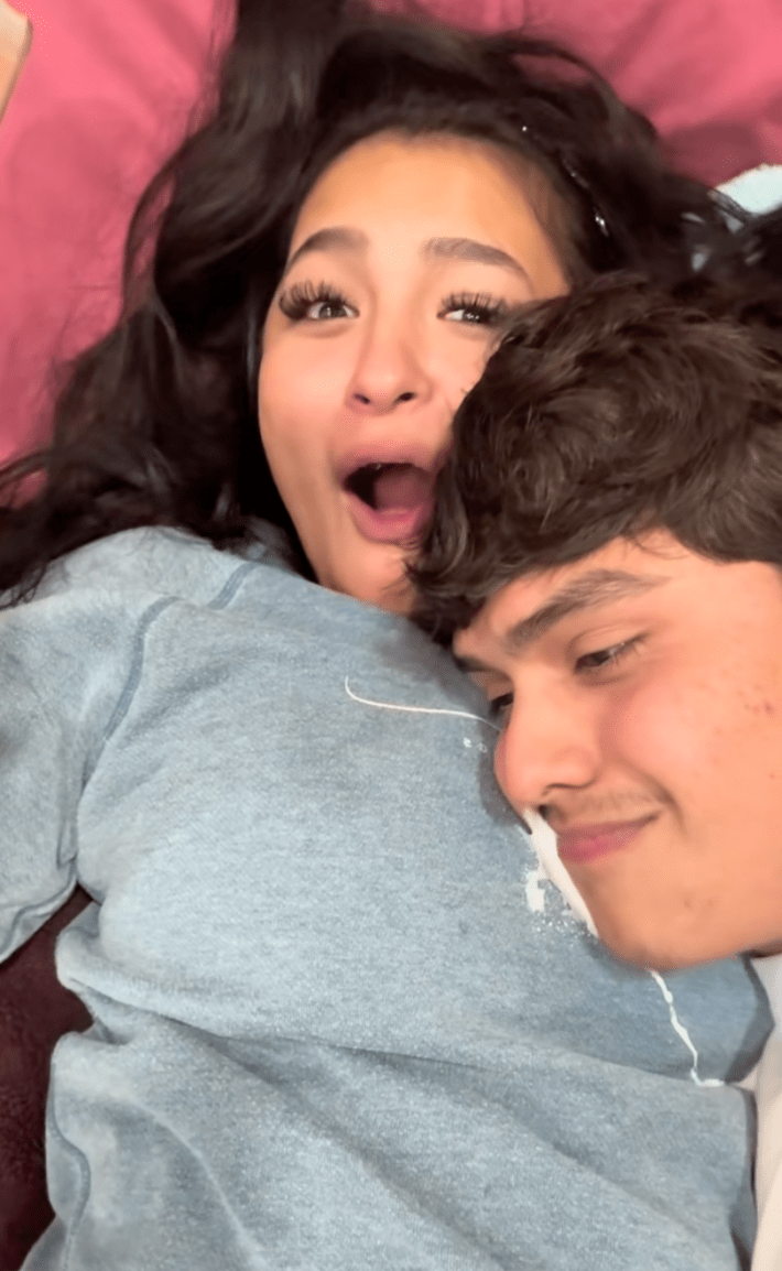 A woman looking completely shocked after her partner spat up milk all over her chest.