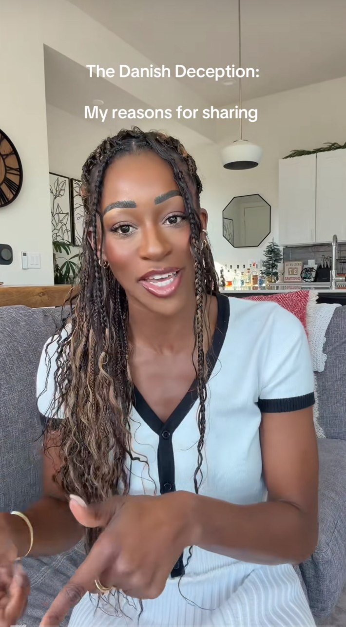 A Black woman sitting down in a sunny room to talk to her camera, gesturing with her hands as she speaks. Text overlay reads, "My reasons for sharing."