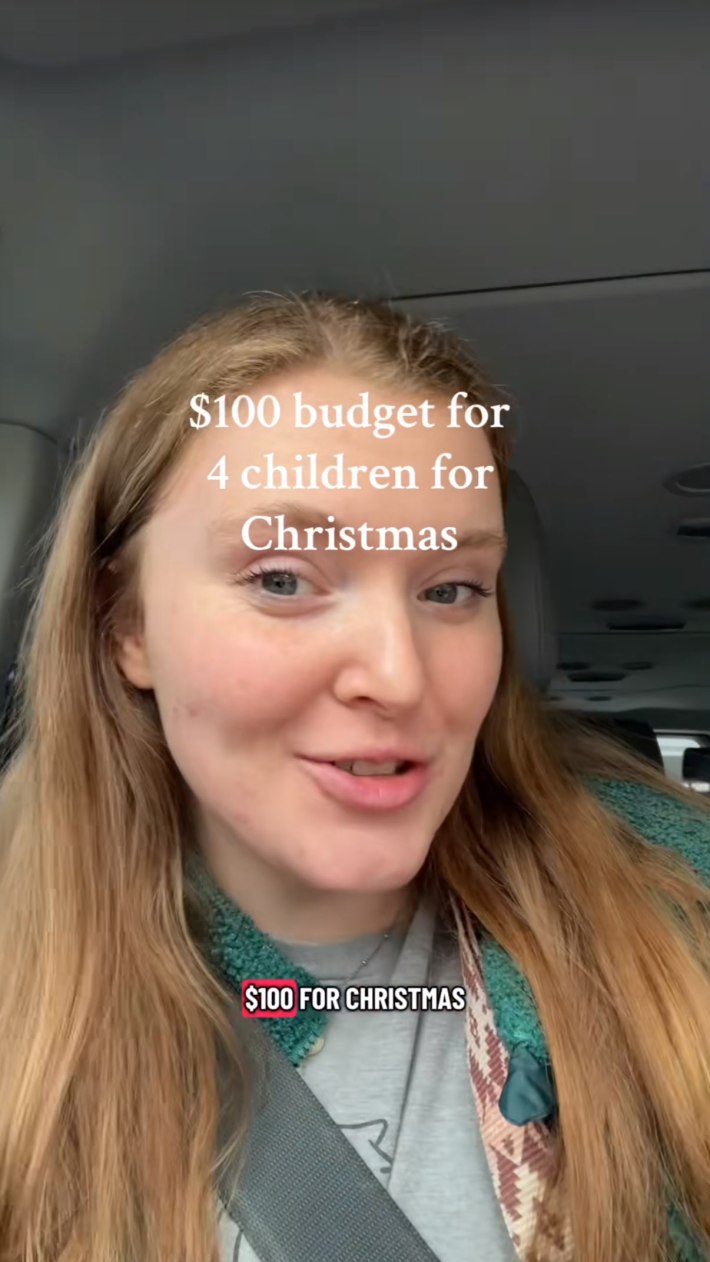 Redheaded woman sitting in her car, smiling. Text overlay reads, "$100 budget for 4 children for Christmas."