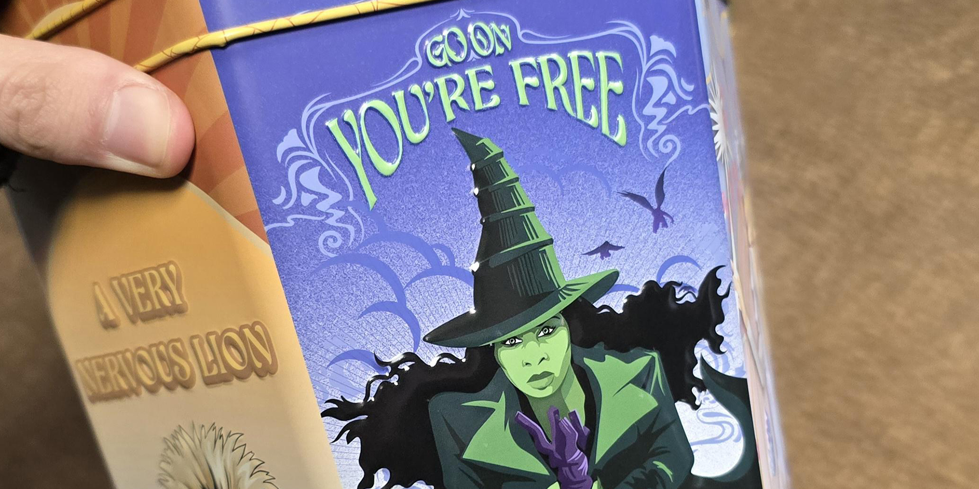 Hand holding new "Wicked" movie theater cup that reads "Go on you're free."