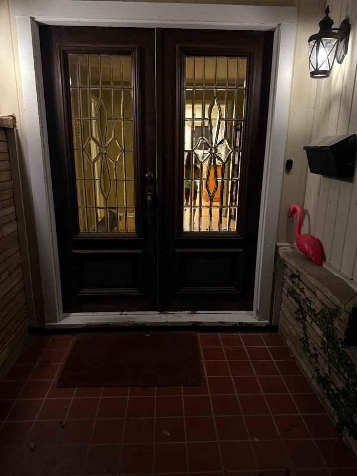 Photo of a fancy-looking front door with a lawn flamingo on a low wall.