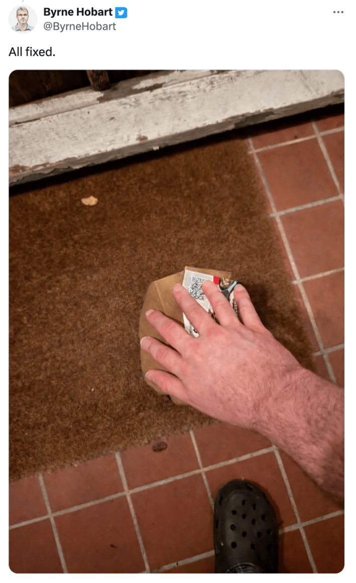 Tweet that reads, "All fixed." with an image of a six-fingered hand on a bag of food.