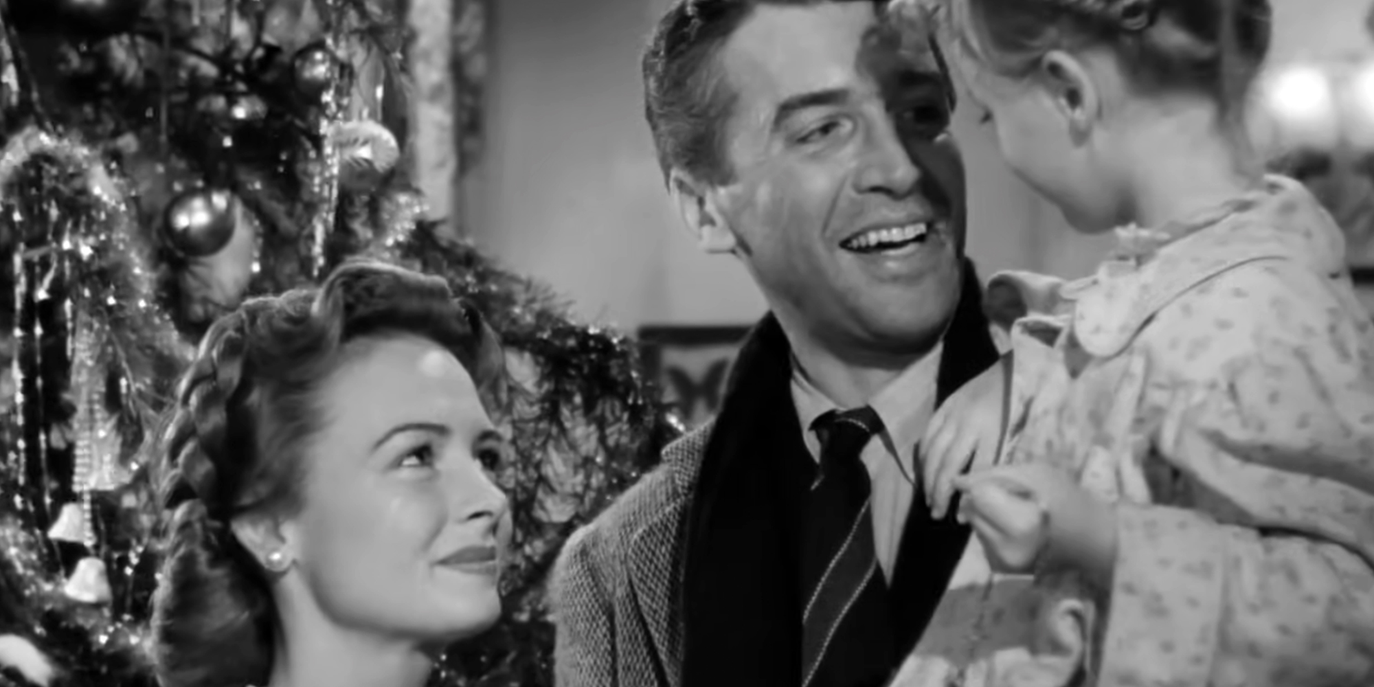 Ending scene in "It's a Wonderful Life," with George Bailey holding his daughter Zuzu next to his wife against a Christmas tree backdrop.