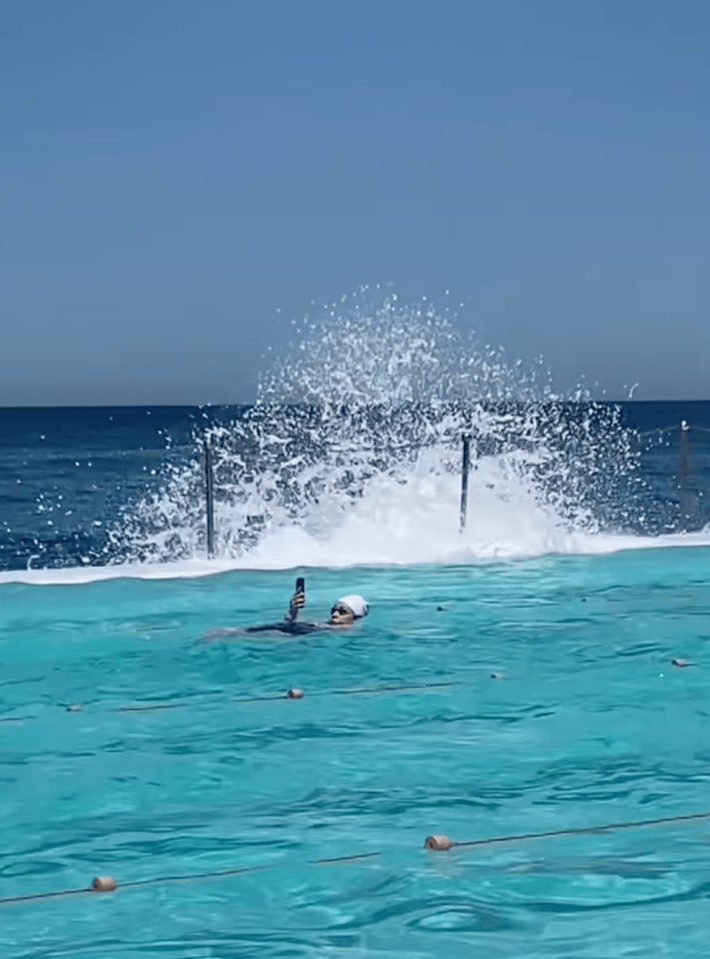 @browncardigan/Instagram swimming laps back stroke in public pool while looking at phone and taking selfie