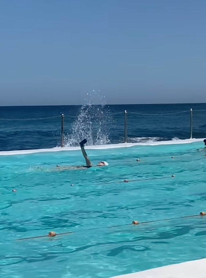 @browncardigan/Instagram swimming laps back stroke in public pool while looking at phone and taking selfie