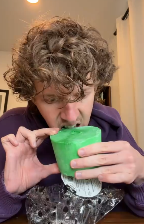 TikTok video of a man biting into a large green horse treat in his home.