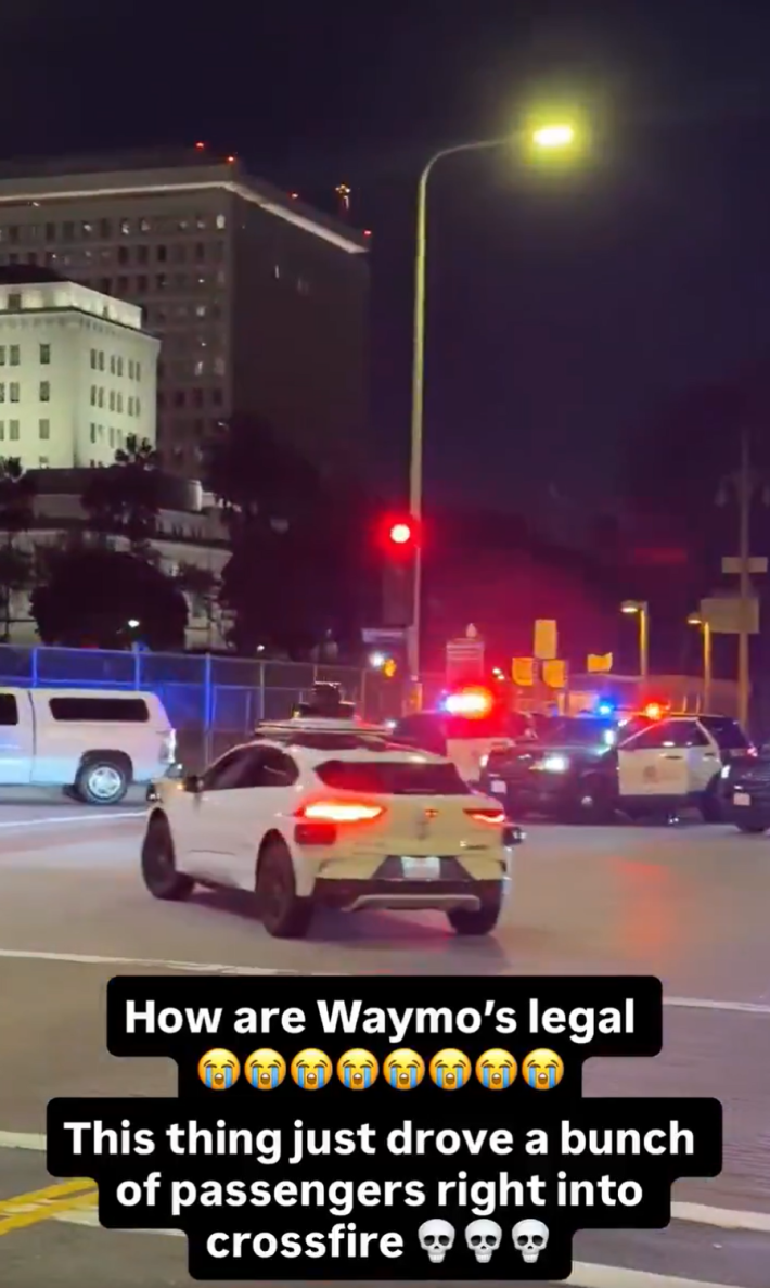 Waymo car driving through a police standoff at night. Text overlay reads, "How are Waymo's legal. This thing just drove a bunch of passengers right into crossfire."