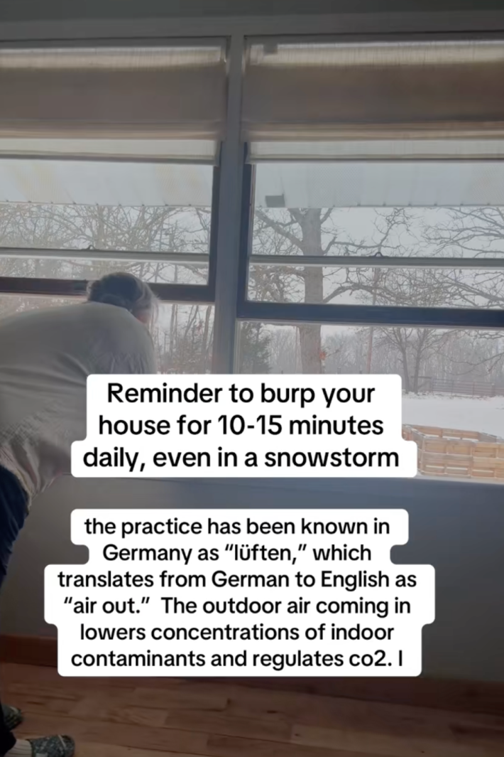 @fasciacodes/TikTok woman opening a window with onscreen text: "Reminder to burp your house for 10-15 minutes daily, even in a snowstorm. The practice has been known in Germany as 'lüften' which translates from German to English as 'air out.' The outdoor air coming in lowers concentrations of indoor contaminants and regulates CO2."