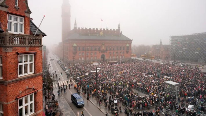 An overhead angled view of the crowd of protesters in Greenland, many wearing the spoof red hats.