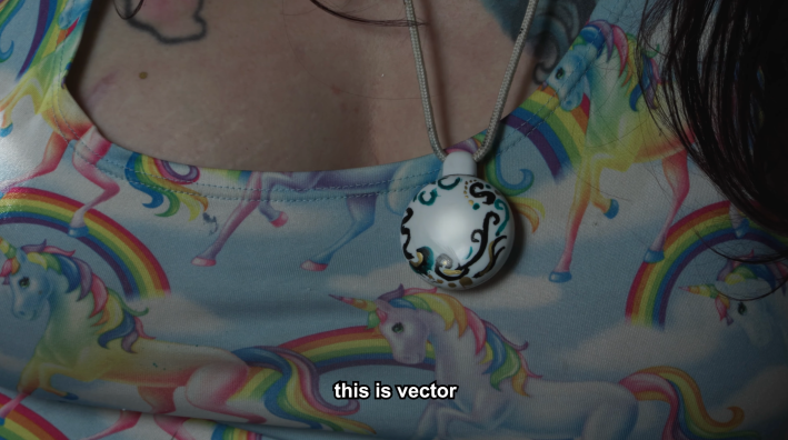 Closeup of the "friend" necklace, which she has customized with marker. The text says "this is vector."