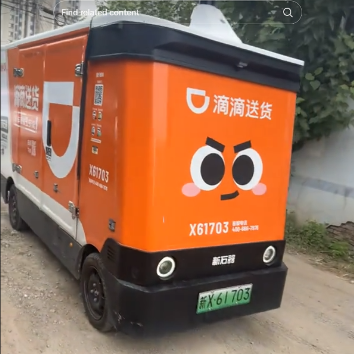 Van de entrega sem motorista laranja em uma estrada de terra com um rosto bonito pintado na frente.