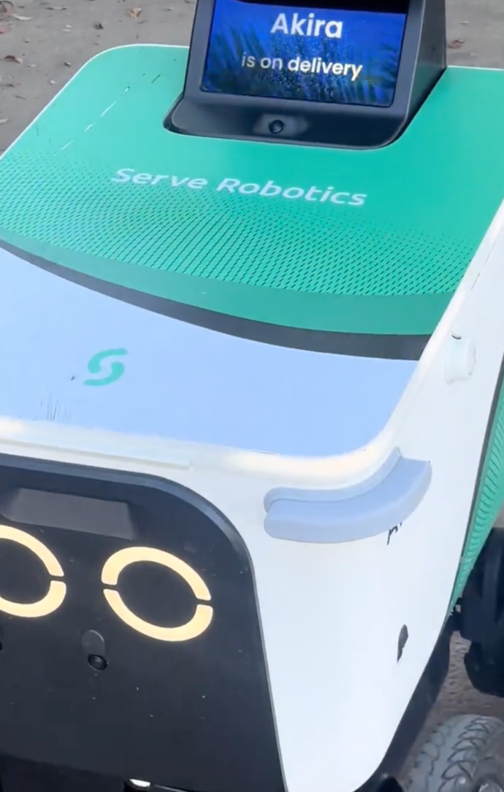autonomous sidewalk food delivery robot navigates around a man asleep on the street in Miami