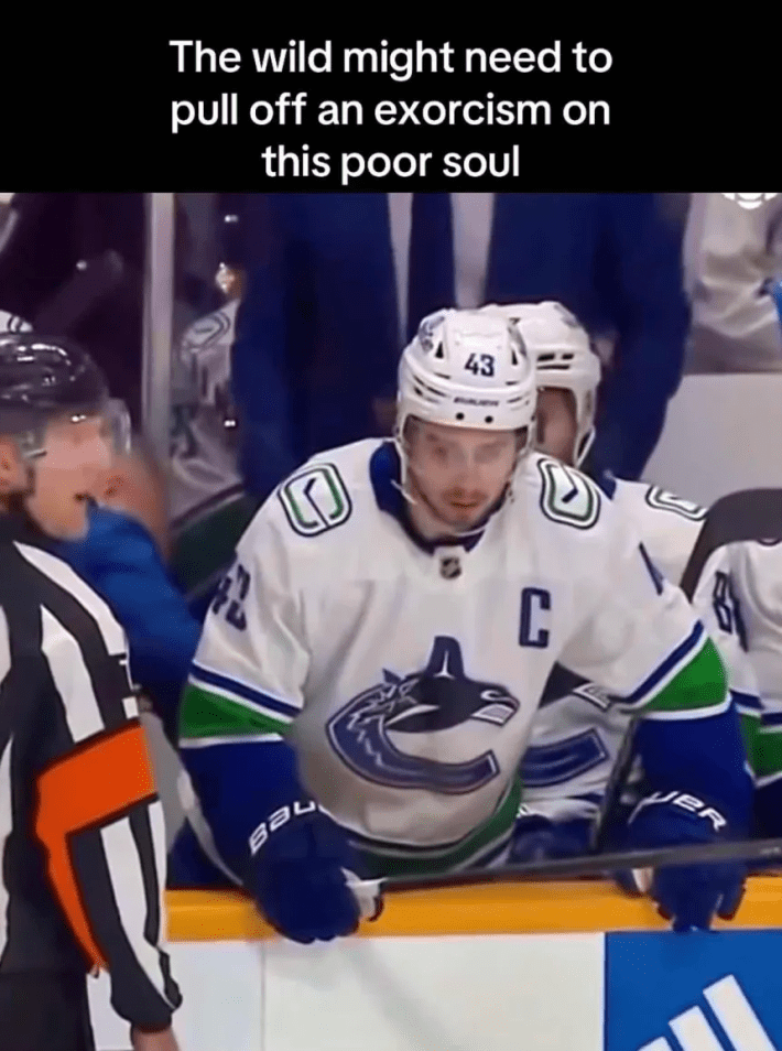 Quinn Hughes disassociating and staring off into space from the bench. Text overlay reads, "The wild might need to pull off an exorcism on this poor soul."