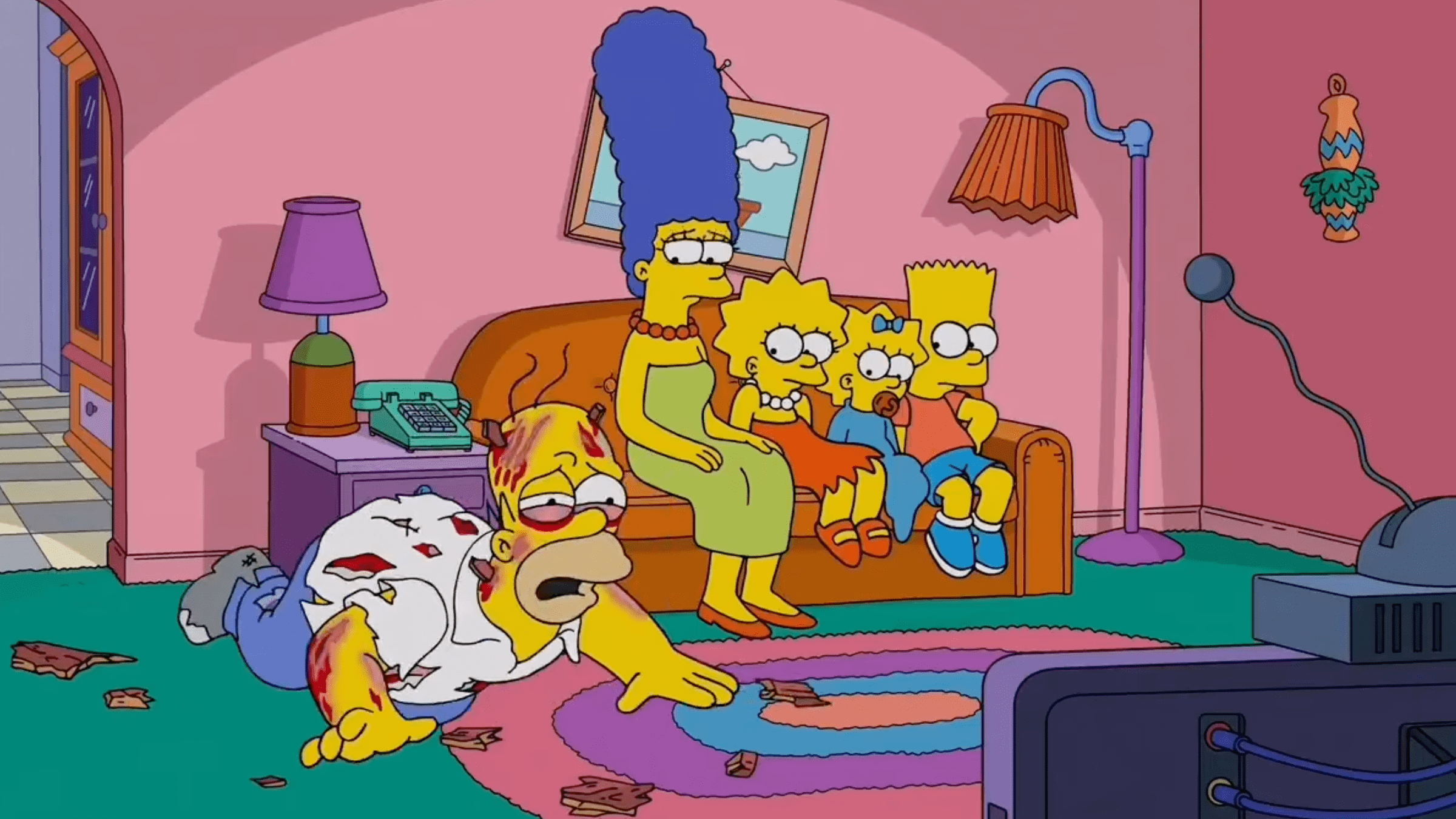 the simpsons sitting on the couch while homer lays on the ground injured