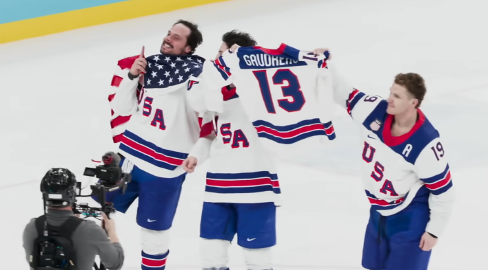 team usa olympians celebrating on the ice with an american flag in hand