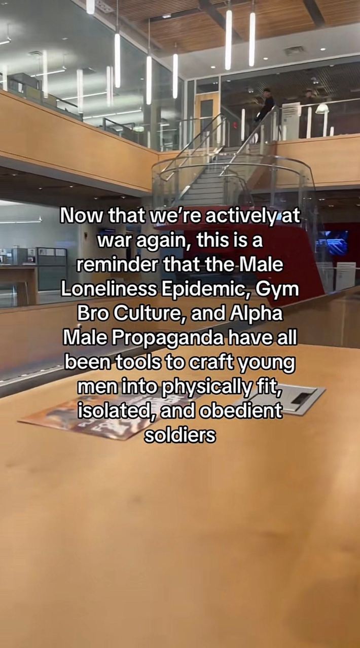 Scene in an empty building. Text overlay reads, "Now that we're actively at war again, this is a reminder that the Male Loneliness Epidemic, Gym Bro Culture, and Alpha Male Propaganda have all been tools to craft young men into physically fit, isolated, and obedient soldiers."