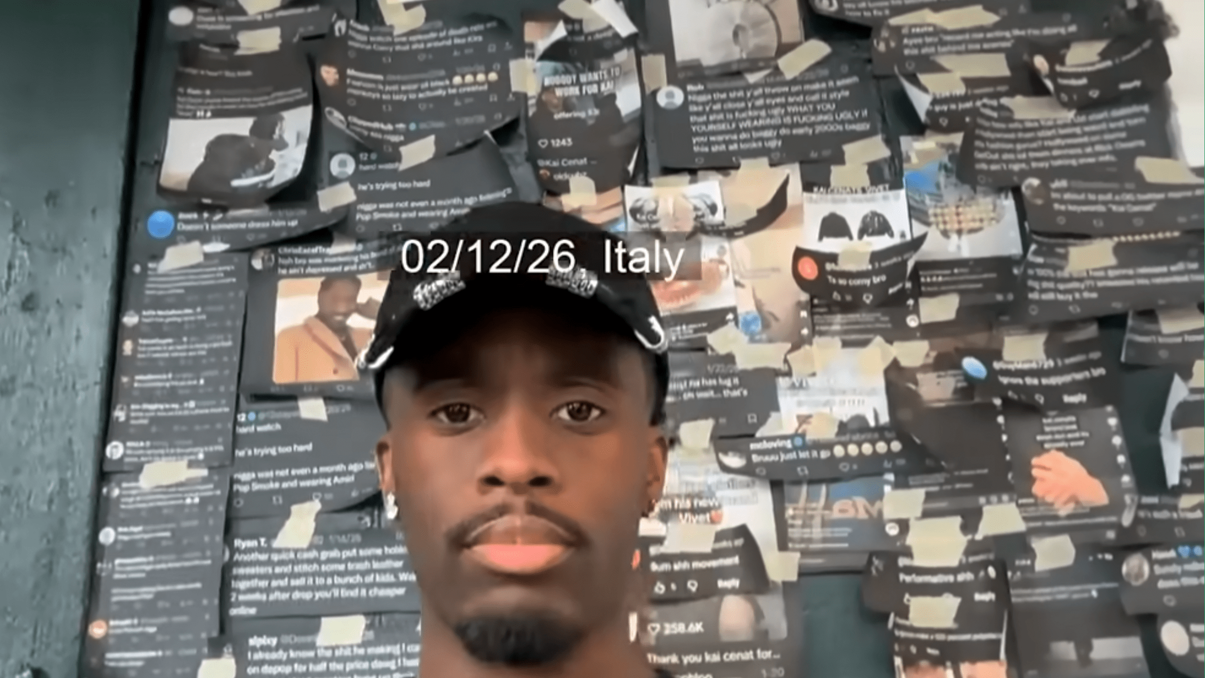 kai cenat in front of a wall of printed out tweets