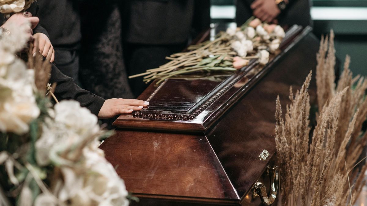 Mourners gathered around a casket topped with flowers