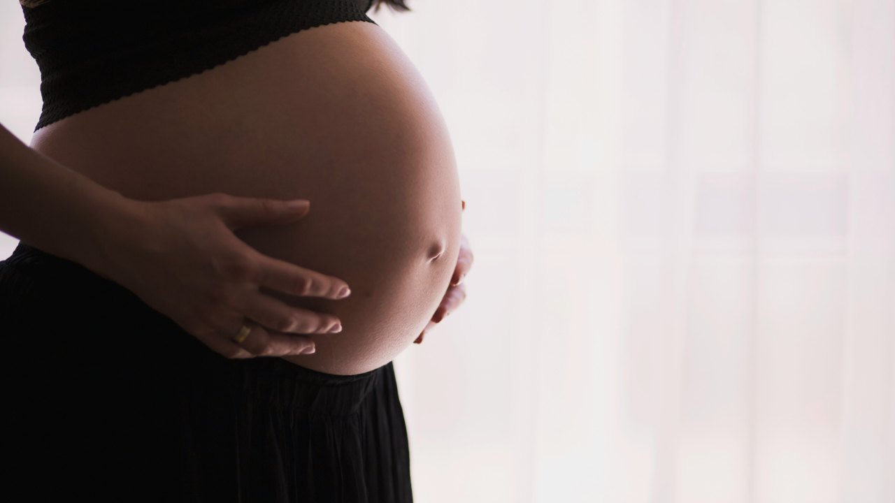 Pregnant woman cradles her belly.