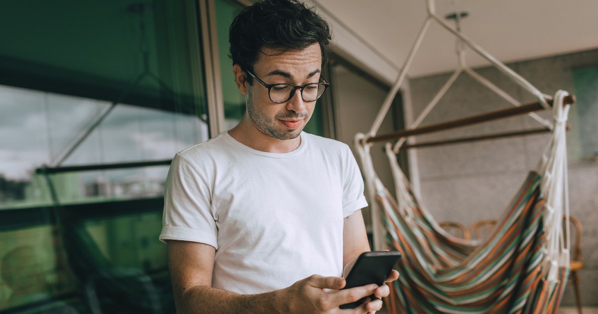 Man looking at his phone while standing outside.